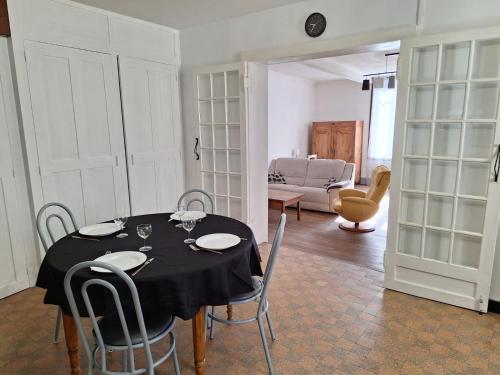 une salle à manger avec une table et des chaises noires dans l'établissement La Maison Douessine - Hyper Centre Doué La Fontaine - WIFI gratuit -Proche Bioparc Zoo, à Doué-la-Fontaine