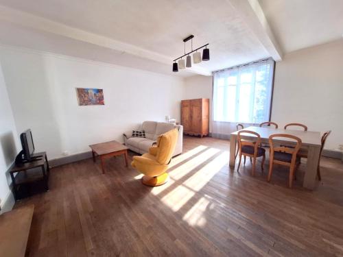 een woonkamer met een bank, een tafel en stoelen bij La Maison Douessine - Hyper Centre Doué La Fontaine - WIFI gratuit -Proche Bioparc Zoo in Doué-la-Fontaine