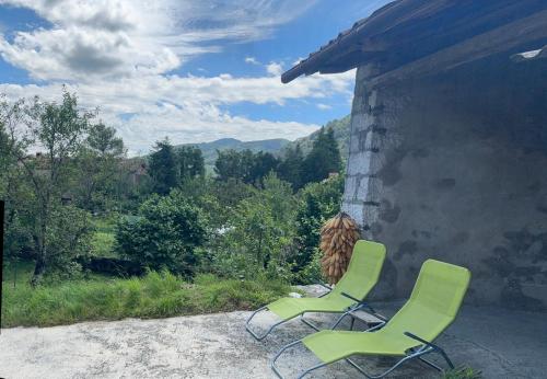two green chairs sitting on the side of a building at Pri Piskovih in Grgar