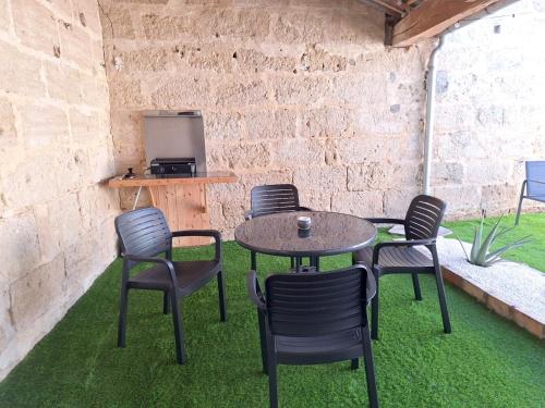 een patio met een tafel en stoelen op het gras bij La Maison Douessine - Hyper Centre Doué La Fontaine - WIFI gratuit -Proche Bioparc Zoo in Doué-la-Fontaine