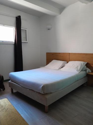 a bedroom with a bed with a wooden headboard and a window at Le palais, hôtel - restaurant in Apt
