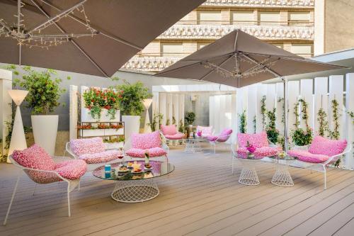 a room with pink chairs and tables and an umbrella at NH Collection Madrid Abascal in Madrid