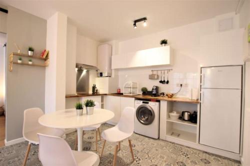 une cuisine avec une table et des chaises et un réfrigérateur blanc dans l'établissement Toulouse grand T2 climatisé Proche Place Dupuy, à Toulouse