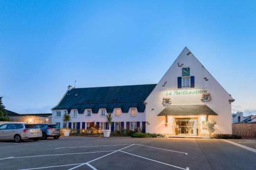 a large white building with a car parked in a parking lot at Quality Hotel La Marebaudière Vannes Centre in Vannes