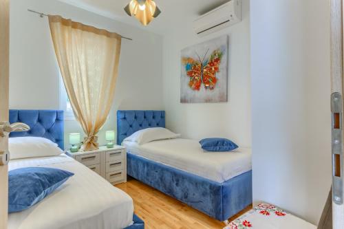 two beds in a bedroom with blue accents at Villa ARIJANA - LAVANDA in Slatine