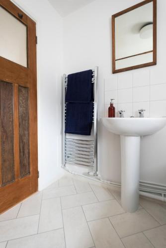 a white bathroom with a sink and a mirror at Character cottage in the heart of Uplyme. in Uplyme