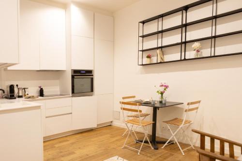 une cuisine avec des armoires blanches et une table avec des chaises dans l'établissement La Sorbonne Fleurie, à Paris