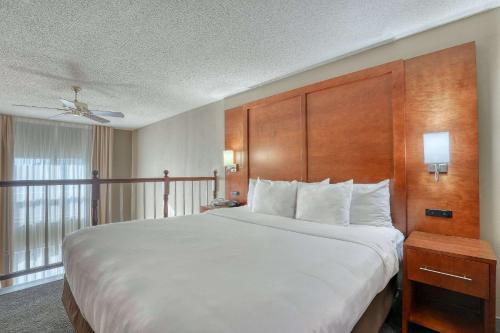 a bedroom with a large white bed with a wooden headboard at Comfort Suites Madison West - Middleton in Madison