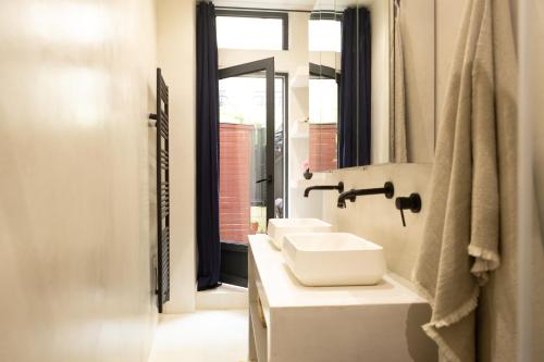 une salle de bain blanche avec deux lavabos et un miroir dans l'établissement La Sorbonne Fleurie, à Paris