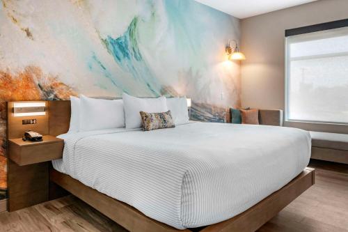 a bedroom with a large bed with a painting on the wall at Cambria Hotel Orlando Airport in Orlando