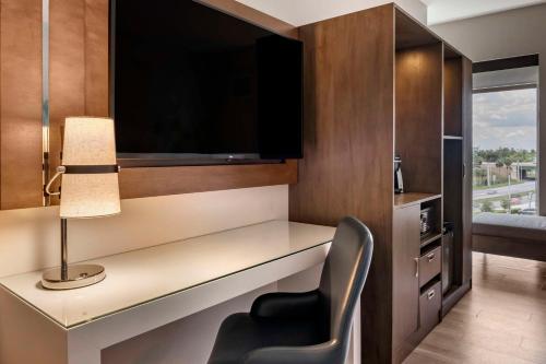 a room with a desk with a lamp and a chair at Cambria Hotel Orlando Airport in Orlando