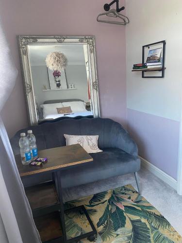 a living room with a blue couch and a mirror at Room in house with breakfast incuded in Llantwit Major