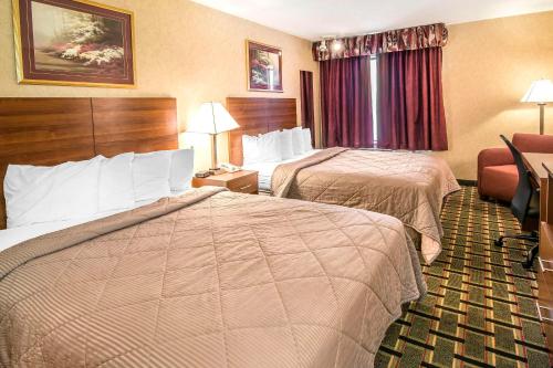 a hotel room with two beds and a chair at Quality Inn Raton, NM in Raton