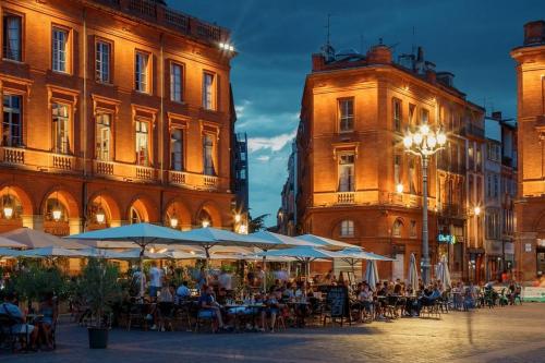 un groupe de personnes assises aux tables devant les bâtiments dans l'établissement Souriez c'est convivial, à Toulouse