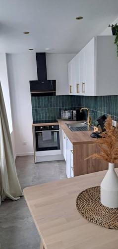 une cuisine avec des placards blancs et un vase sur une table dans l'établissement Le balinais , en hyper centre rue au calme avec parking, à Cherbourg en Cotentin