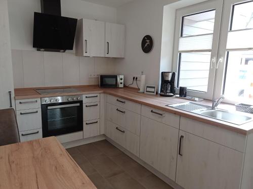 Una cocina con gabinetes blancos, un fregadero y un microondas. en Ferienhaus Ebsen HH 2, en Steinberg