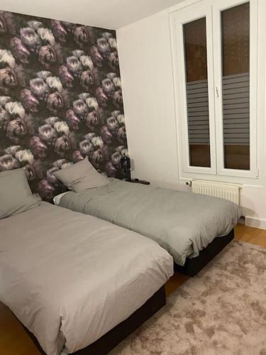 - 2 lits dans une chambre avec papier peint floral dans l'établissement Le Brétigny Logement 6 personnes, à Joinville-le-Pont