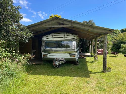 a rv parked under a shed in a yard at The Quarry Caravan in Falmouth