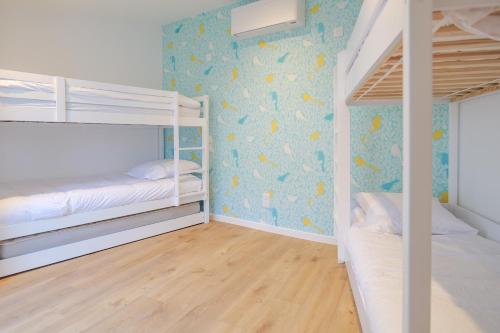 une chambre avec deux lits superposés et un mur bleu dans l'établissement Jolie maison rénovée quartier Arago, à 5 min à pied de la plage des Sables - 6 personnes, à Les Sables-dʼOlonne