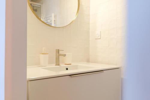 une salle de bain blanche avec un lavabo et un miroir dans l'établissement Jolie maison rénovée quartier Arago, à 5 min à pied de la plage des Sables - 6 personnes, à Les Sables-dʼOlonne