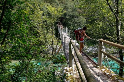 two people on a suspension bridge over a river at Apartma na podeželju Marta- Slovenia Nature in Kanal