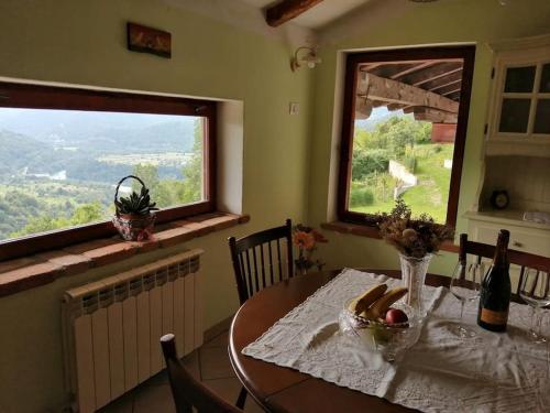 a dining room with a table and two windows at Apartma na podeželju Marta- Slovenia Nature in Kanal