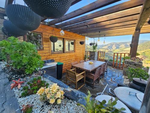 a patio with a table and a kitchen with mountains in the background at Quinta da Valdigueira in Armamar