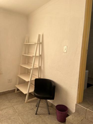 a black chair sitting next to a wall with a ladder at African Violet in Mbabane