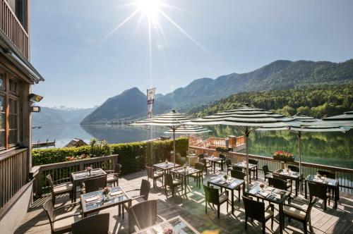 a patio with tables and chairs and a view of a lake at TAUROA Seehotel Grundlsee in Grundlsee
