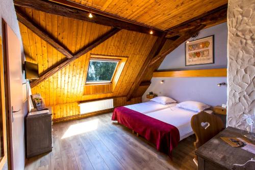 une chambre avec un lit et un plafond en bois dans l'établissement Le Bouton d'Or, à Lapoutroie
