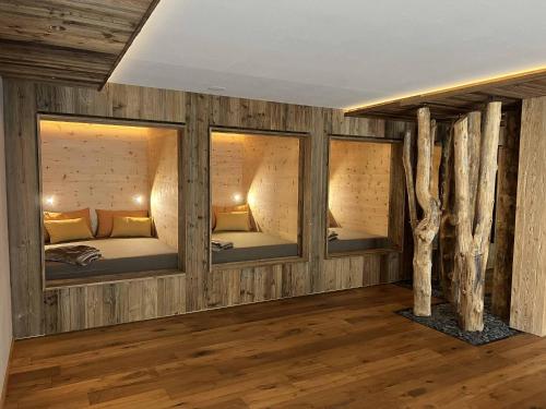 a room with three beds in a room with trees at Appartements Pohuibe in Anterselva di Mezzo
