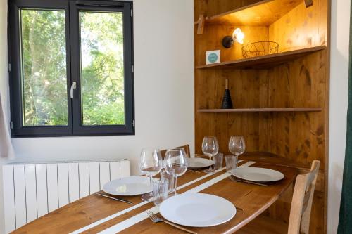a wooden table with glasses and plates on it at La Cabane Ô Rêves in Genouilleux