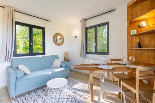 un salon avec un canapé bleu et une table dans l'établissement La Cabane Ô Rêves, à Genouilleux