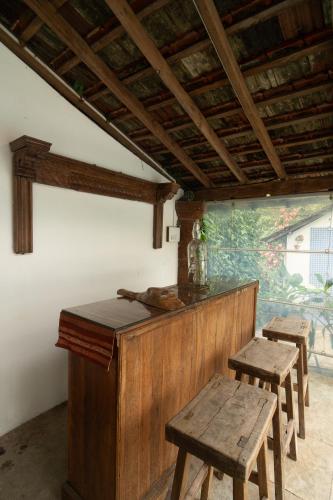 a wooden bar with benches and tables in a room at Island House Goa in Divar