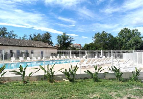 une piscine avec des chaises blanches et une clôture dans l'établissement Studio 3 - LES SUITES DE ROBINSON - Résidence avec piscine en bord de Siagne, à Mandelieu-La-Napoule, à Mandelieu-la-Napoule