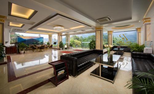 a living room with black leather couches and a table at Sapa Praha Hotel in Sa Pa