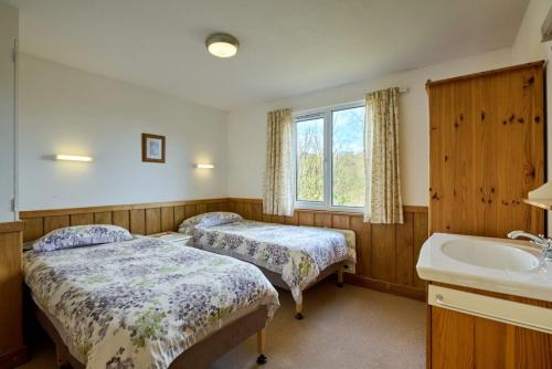 una habitación con dos camas y un lavabo y una bañera en Churchwood Valley, en Plymouth
