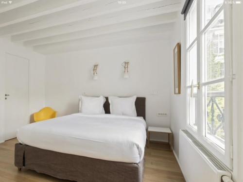une chambre blanche avec un grand lit et une fenêtre dans l'établissement GuestReady - Elegant and Cozy Apt in 3rd ARR., à Paris