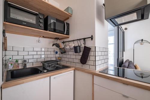 une cuisine avec un évier et un micro-ondes dans l'établissement GuestReady - T1 BIS - Cosy and Lovely, à Lyon