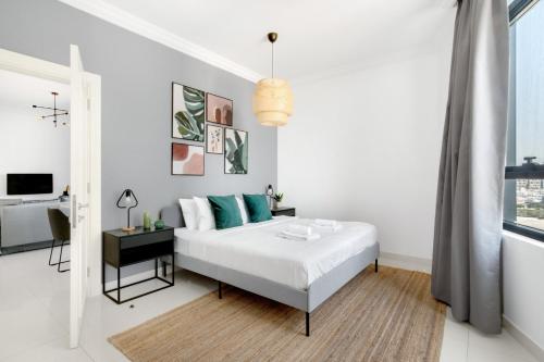 ein weißes Schlafzimmer mit einem Bett und einem Fenster in der Unterkunft GuestReady Holiday Homes - Light Abode in Dubai