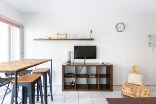 a living room with a table and a tv on a wall at GuestReady - Appartement Cours du Médoc in Bordeaux