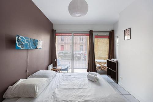 a bedroom with a large bed and a window at GuestReady - Appartement Cours du Médoc in Bordeaux