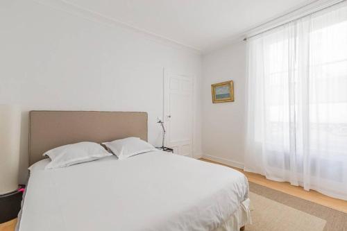 une chambre blanche avec un grand lit et une fenêtre dans l'établissement GuestReady - Bel Apt pour 4 / Luxembourg -Assas, à Paris