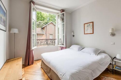 une chambre avec un grand lit blanc et une fenêtre dans l'établissement GuestReady - Bel Apt pour 4 / Luxembourg -Assas, à Paris