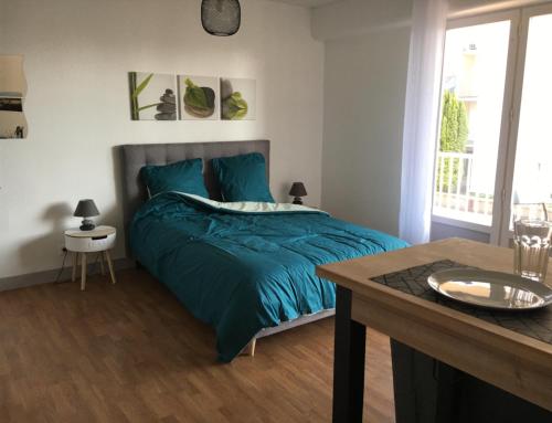 - une chambre avec un lit doté d'une couette bleue et d'une table dans l'établissement Studio Le Saint Paul, Granville, à Granville