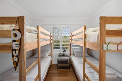 a room with three bunk beds and a window at TwentyTwo on Twynam in Jindabyne