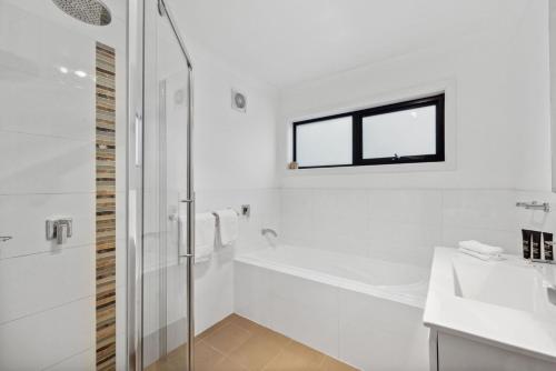 a white bathroom with a shower and a tub and a sink at TwentyTwo on Twynam in Jindabyne