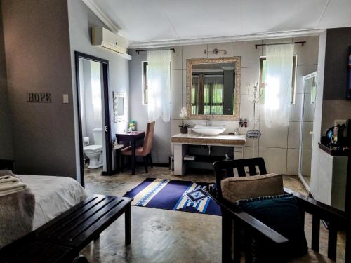 a bathroom with a bed and a sink and a mirror at Winterton Country Lodge @ Rose Cottage in Winterton