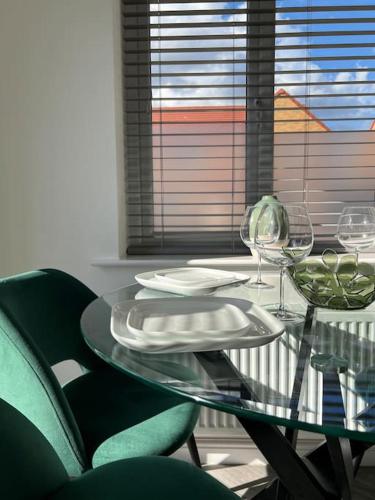 a glass table with plates and wine glasses on it at Beautiful 3 Bed Detached House in Grimsby in Little Coates