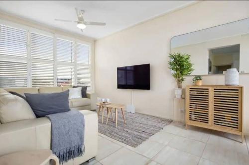 a living room with a couch and a tv at Beachside retreat with ocean views in Glenelg in Glenelg